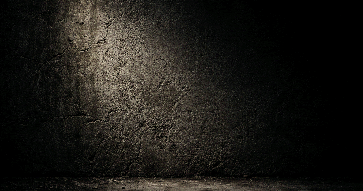暗い空間に立つ質感のあるコンクリート壁と片側から差し込む光のリアルな写真風イメージ