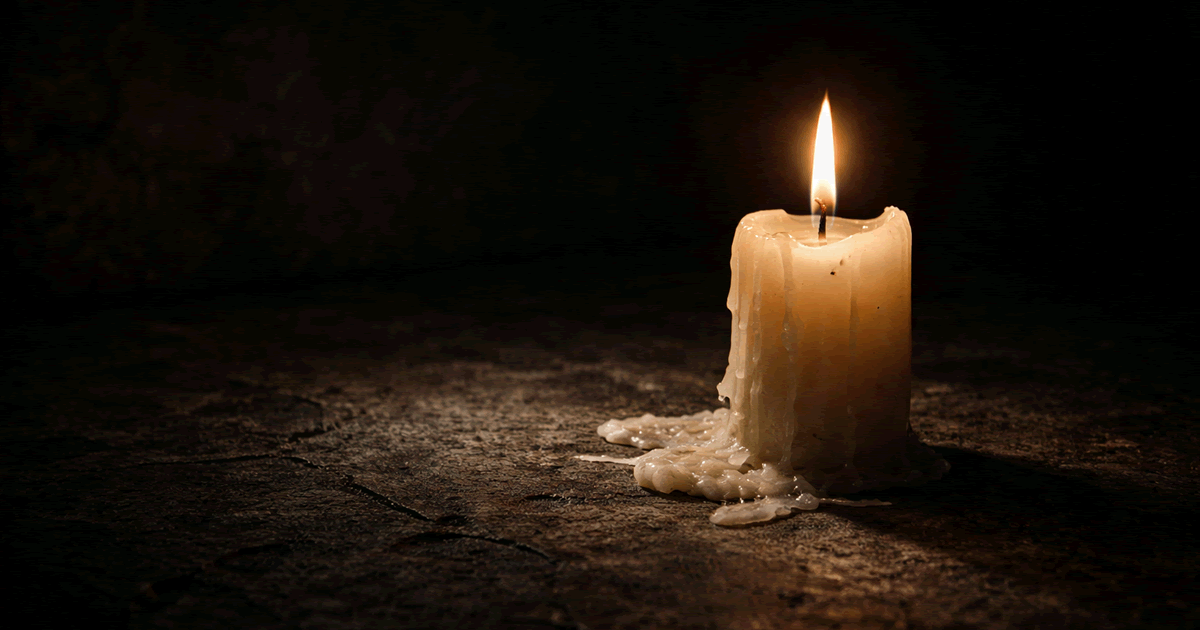 暗闇の中で揺れる一本のロウソクの炎